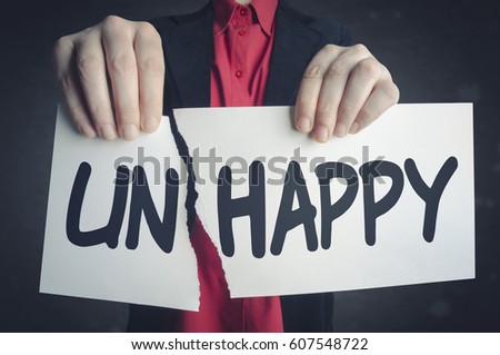 Businessman tearing up a sign saying - Unhappy - conceptual image of positive attitude and transformation.