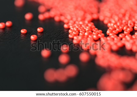 Red seed beads scattered on a dark background