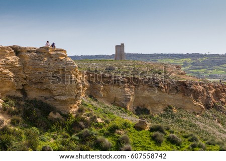 Ta' Lippija Tower, an ancient Knights of St. John Watchtower amid the green and yellow spring wildflowers on a beautiful bright sunny day walking on the costal path above Ghajn Tuffieha, Mgarr, Malta