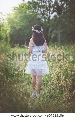 A young woman wearing a crown of flowers, looking at the fairy lights from the nature, shines down as if waiting for the hope that is coming to her in the morning.   