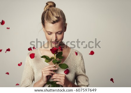 Beautiful woman with red rose petals, studio Royalty-Free Stock Photo #607597649