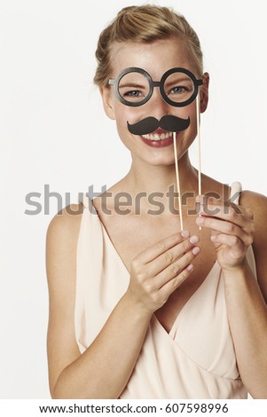 Beautiful woman playing with mustache and spectacles disguise