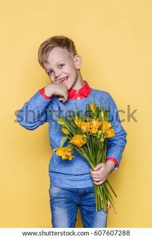 Little beautiful child with a bouquet of tulips. Son gives mom flowers on Women's Day, Mother's Day. Birthday. Valentine's day. Spring. Studio portrait over yellow background