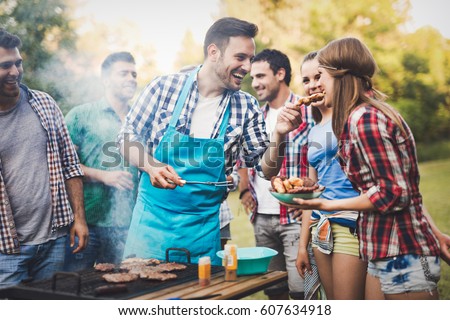 Friends having a barbecue party in nature  while having a blast Royalty-Free Stock Photo #607634918