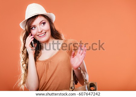 Technology and communication. Attractive summer woman talking on mobile phone orange background