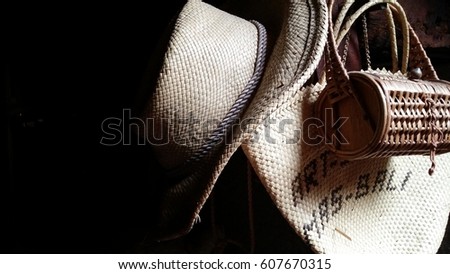 Two bags and a straw hat on a black background.