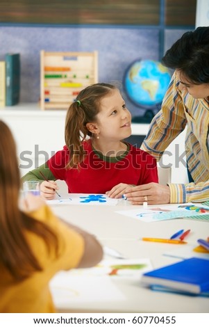 Teacher teaching painting to elementary age children in classroom at primary school.?
