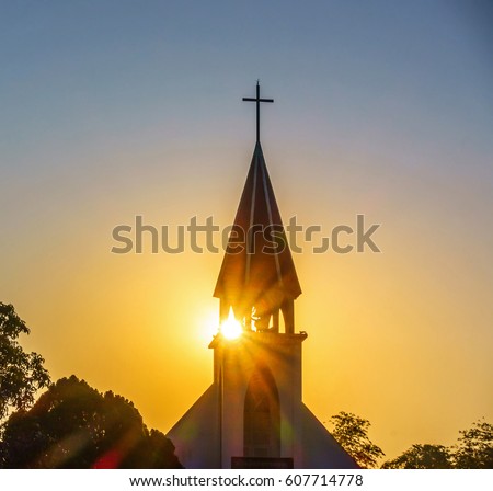The silhouette of the cross and church bell tower in sunrise Royalty-Free Stock Photo #607714778