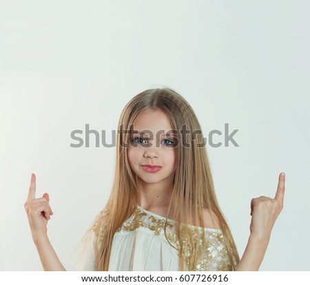 Look up here. Portrait closeup of funny excited girl female child kid smiling girl long hair looking at you pointing showing up isolated white background wall. Positive human emotion facial expression