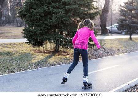 Little girl roller skating outdoor at sunset.
