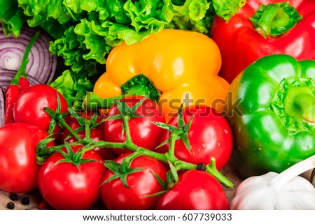 Yellow, green and red bell paper, garlic, tomatoes, onion, green lettuce on stone surface. Beautiful vibrant composition of fresh organic vegetables. Royalty-Free Stock Photo #607739033