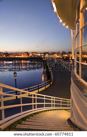 Breathtaking picture along pier back to seafront town alight with glow of evening lights in town