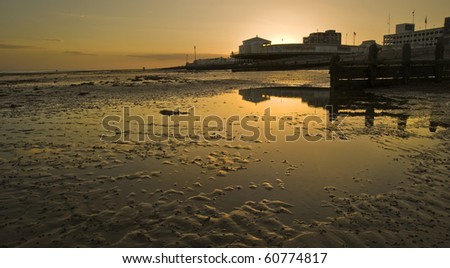 Golden sunset reflecting in low tide water on beach