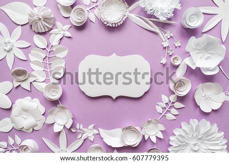 Festive flower composition with white paper flowers with greeting card on the green background. Flat lay, overhead view, top view