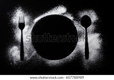 Silhouette of a plate, fork and spoon made my sugar powder on a black background Royalty-Free Stock Photo #607788989