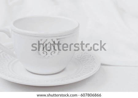 White relief ceramic tea cup with saucer on wood table cotton fabric, purity concept, minimalist, styled image for social media, banner, header