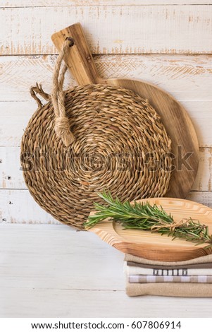Wood cutting board, rattan coaster, stack of linen towels on wood table, mockup, styled image, kitchen interior background