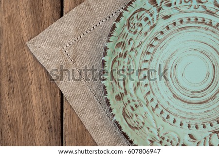 Empty vintage relief plate on linen napkin on plank wood table, top view, flat lay, mockup, menu template, product marketing styled image