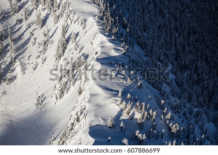 Aerial landscape view on the mountain ridge covered in snow with skiers on the top. Picture taken near Howe Sound, North of Vancouver, BC, Canada.