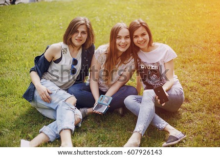 three beautiful girls walking in the park and take pictures on your phone