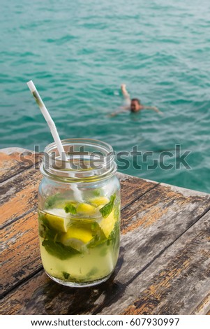 Mojito coctail on a wooden table in front of the sea.
