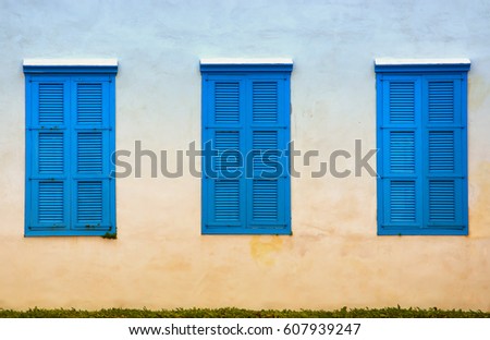 wall of old building and blue windows with shutters.