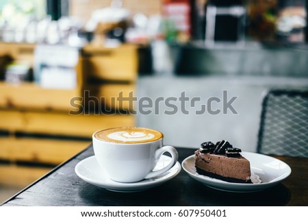 Latte Art or Hot Coffee Cup with chocolate cake on brown wooden table in cafe,Soft focus and darktone.