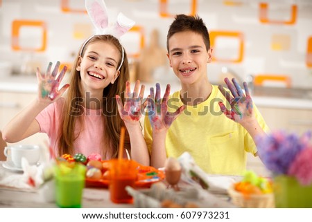 Cheerful children show colorful painted hands with paint for eggs