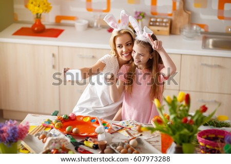 Mother with daughter making selfie while painting Easter eggs 