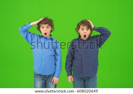 The two surprised twin kids gesture on the green background
