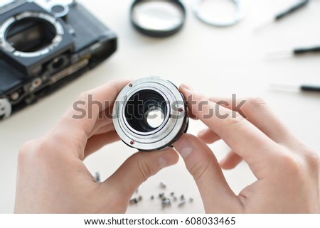 Repair camera lens. The engineer-technician checks the optics and carries out maintenance and cleaning of the broken vintage lens of the camera. Top view of the workplace and the hands of the engineer