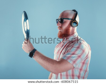 The portrait of bald bearded man photographer with redshirt holding different things, isolated on blue background. High definition HD.
