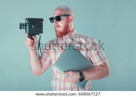 The portrait of bald bearded man photographer with redshirt holding different things, isolated on blue background. High definition HD.