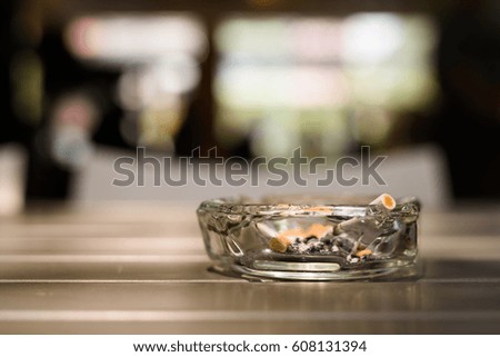 Ashtray with cigarettes on wooden table in restaurant with out of focus background and bokeh effect