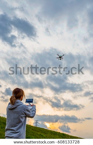 Woman drives a drone towards the cloudy sky