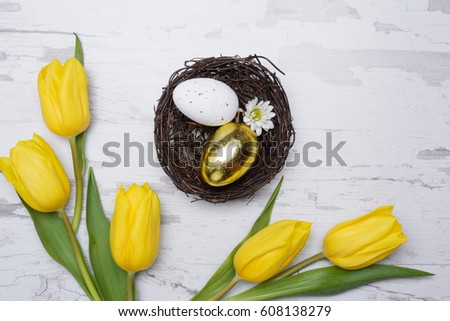 Colored eggs and tulips over wooden background. Easter day photo.