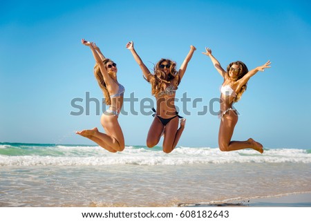 Beautiful teenage friends jumping on the beach Royalty-Free Stock Photo #608182643