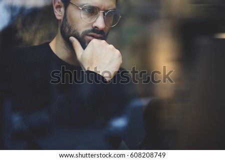 Cropped image of pensive economist in stylish eye glasses reading information on touch pad using internet connection.Close up thoughtful and concentrated business man creating project in loft interior
