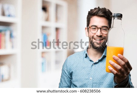 young man offering a bottle of orange juice
