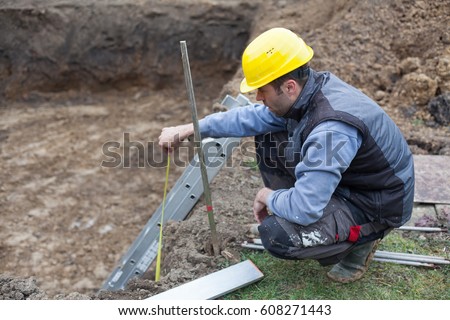 Man working on building a house with a private pool.