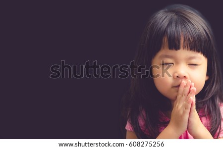 Little girl praying in the morning.Little asian girl hand praying,Hands folded in prayer concept for faith,spirituality and religion.Black  Royalty-Free Stock Photo #608275256