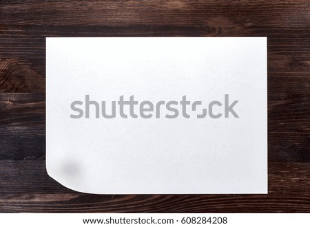 White sheet of paper with a curved bottom corner on a brown wooden surface