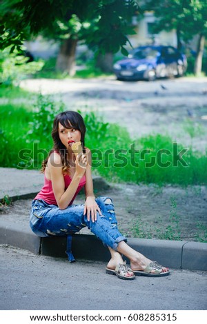beautiful woman eating ice cream sitting on the sidewalk in the city, summer heat.