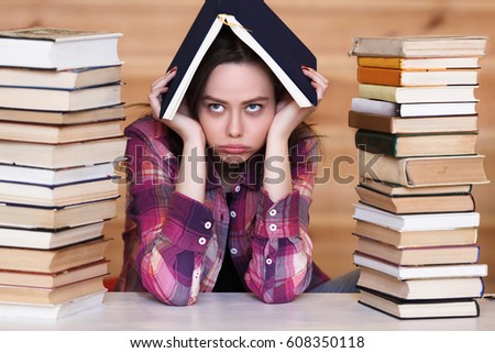 Young woman student tired of working and studying next to the stack of books. Work and study concept