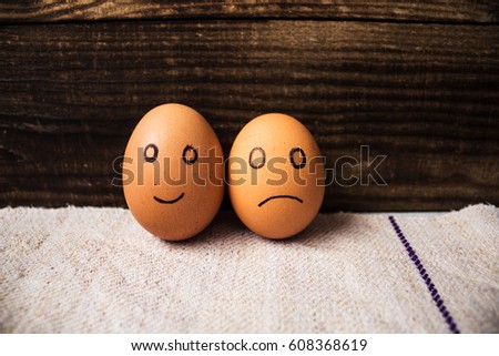 an eggs with drawn emotions on wooden background