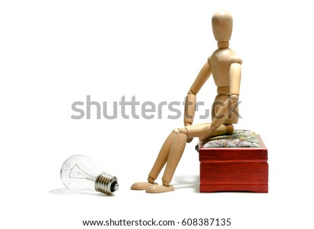 New idea business concept. Man wood figure mannequins sitting on box look on electric bulb and thinking about new ideas.