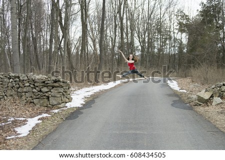 Young girl ballet dancer ballerina dancing on a road in the forest on a cold winter day with snow on the ground.