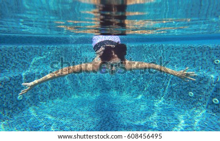 Young asian woman having fun underwater in swimming pool.