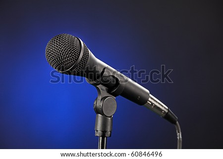 A single microphone close up isolated against a spotlight blue background.