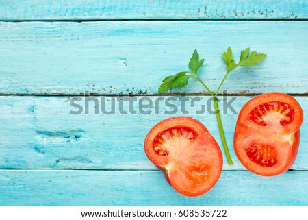 Fresh juicy tomato and green parsley on blue wooden background top view blank space for text